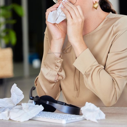 Iemand met tissues achter bureau